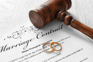 Low Conflict Divorce Lawyer Ogden, UT - Golden wedding rings with judge gavel on marriage contract, closeup